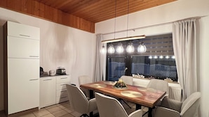 A modern kitchen with a wooden ceiling, white cabinetry, and a dining area with a wooden table and chairs. - Vacation apartment 1 at Steinhuder Meer - near 'Alte Moorhütte'  (Neustadt am Rübenberge)