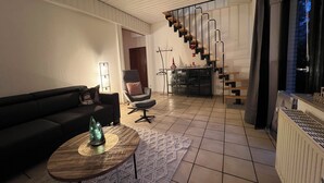 A modern living room with a sofa, a coffee table, and a staircase with a railing. - Vacation apartment 1 at Steinhuder Meer - near 'Alte Moorhütte'  (Neustadt am Rübenberge)
