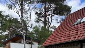 A residential property with a red-tiled roof, a wooden fence, and a small patio area with a table and chairs. - Vacation apartment 1 at Steinhuder Meer - near 'Alte Moorhütte'  (Neustadt am Rübenberge)