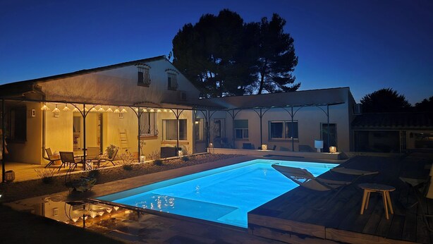 Une maison moderne dotée d’une piscine, d’un espace salon extérieur et d’un patio couvert.