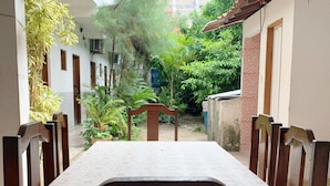 A dining area with a table and chairs, surrounded by greenery and buildings. - Pousada Estilo Brasil (Fortaleza)