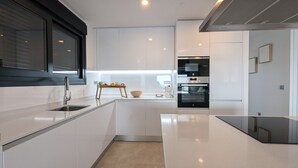 Una cuina moderna amb armaris blancs, tauleig negre i forn integrat.
