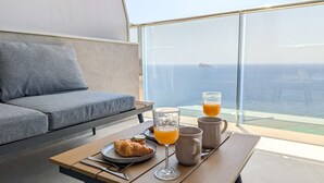 Un petit-déjeuner composé de croissants, de jus d’orange et de café, servi sur un balcon avec vue sur l’océan.
