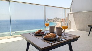 Un balcon avec une table préparée pour le petit-déjeuner, donnant sur une plage et l’océan.