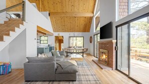 A modern living room with a grey sectional sofa, wooden flooring, a fireplace, and a staircase leading to an upper level.