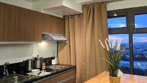A modern kitchen with wooden cabinets, a stainless steel sink, and a wooden dining table. - 59sq/m Spacious and Safe condo+free parking+Manila Bay Sunset view/WiFi&NetFlx (Pasay)