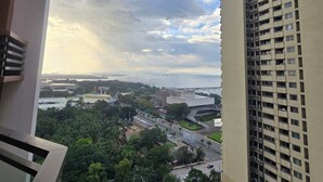 A high-rise building with a view of a cityscape, including a body of water and greenery. - 59sq/m Spacious and Safe condo+free parking+Manila Bay Sunset view/WiFi&NetFlx (Pasay)