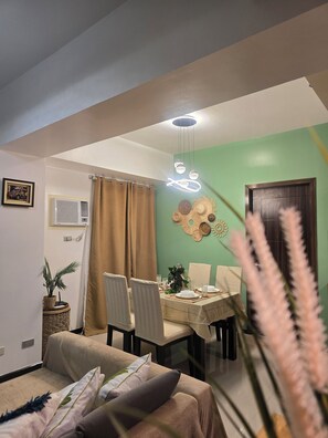 A dining area with a table set for four, a ceiling light fixture, and a wall-mounted air conditioner. - 59sq/m Spacious and Safe condo+free parking+Manila Bay Sunset view/WiFi&NetFlx (Pasay)