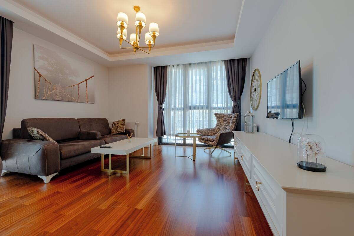 A modern living room with a sofa, armchair, coffee table, and a TV on a stand.