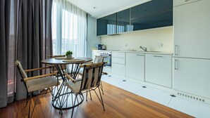 Une cuisine moderne avec des meubles blancs, un four encastré et un coin repas comprenant une table ronde et quatre chaises.