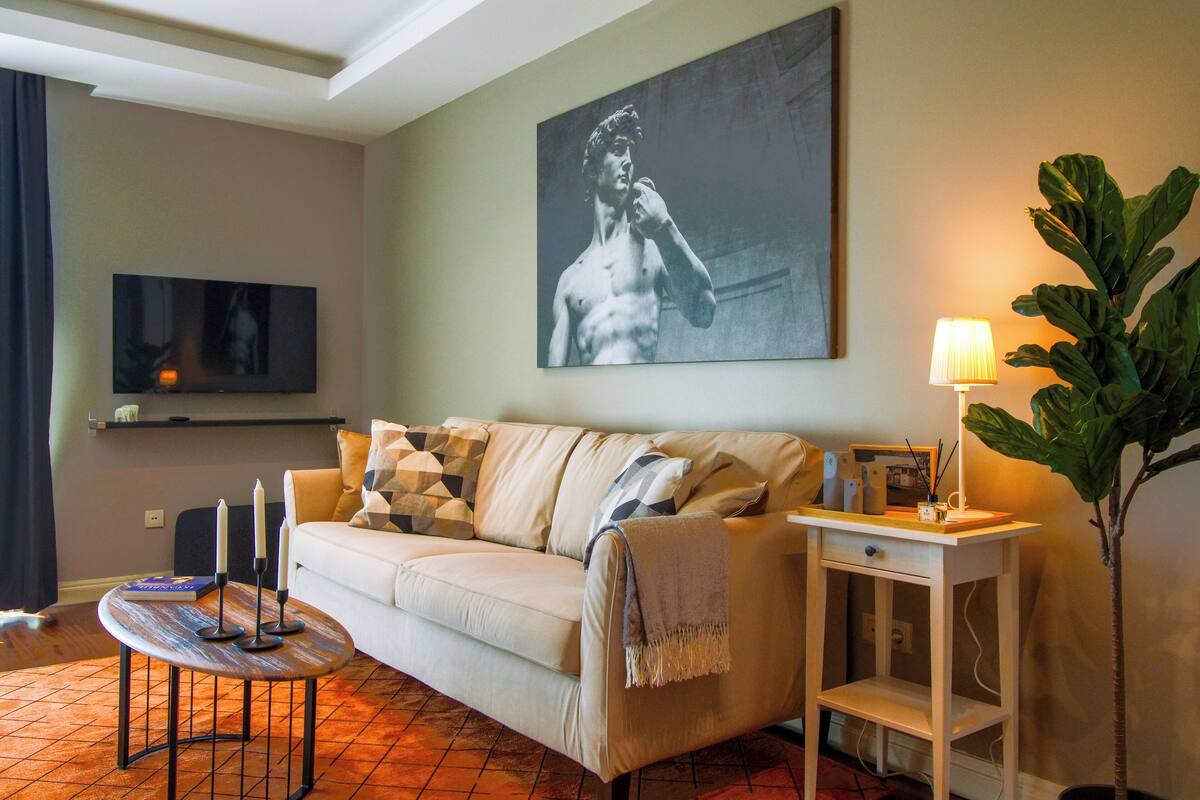 A living room with a sofa, a coffee table, a lamp, a television, and a painting on the wall.
