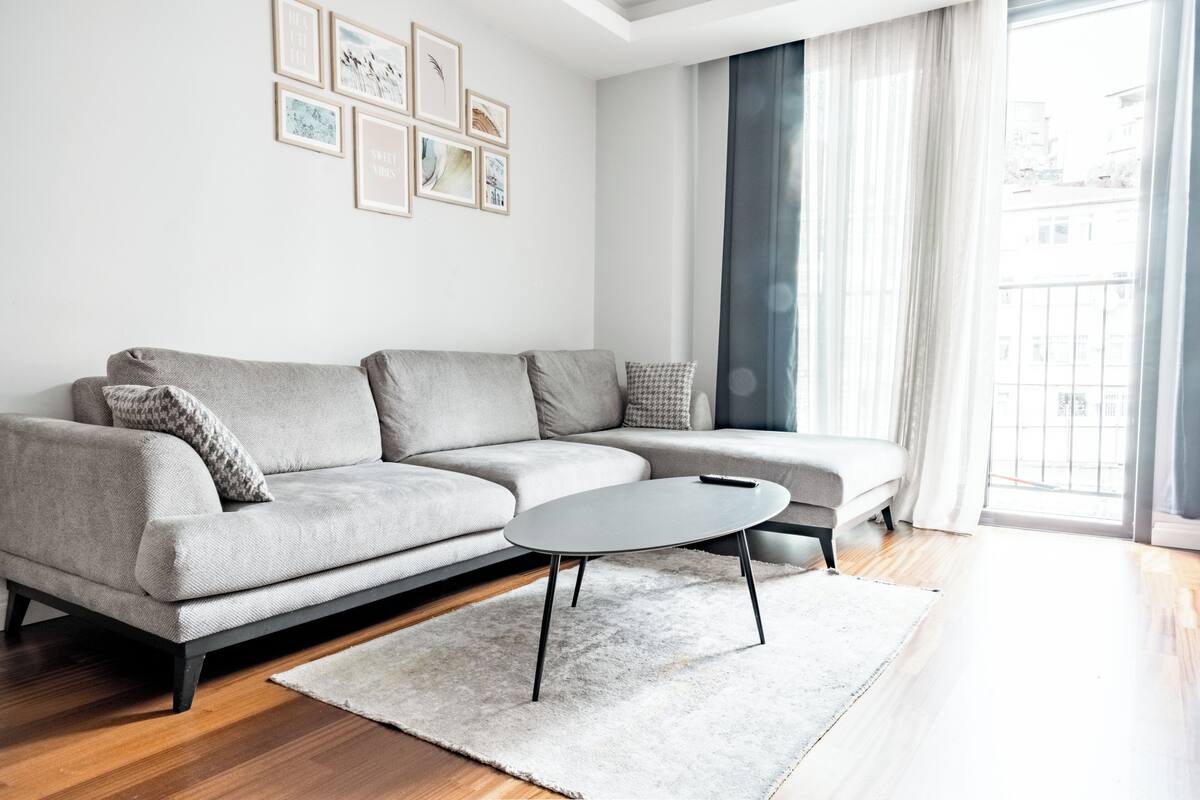 A modern living room with a grey sofa, a round coffee table, and a white rug.