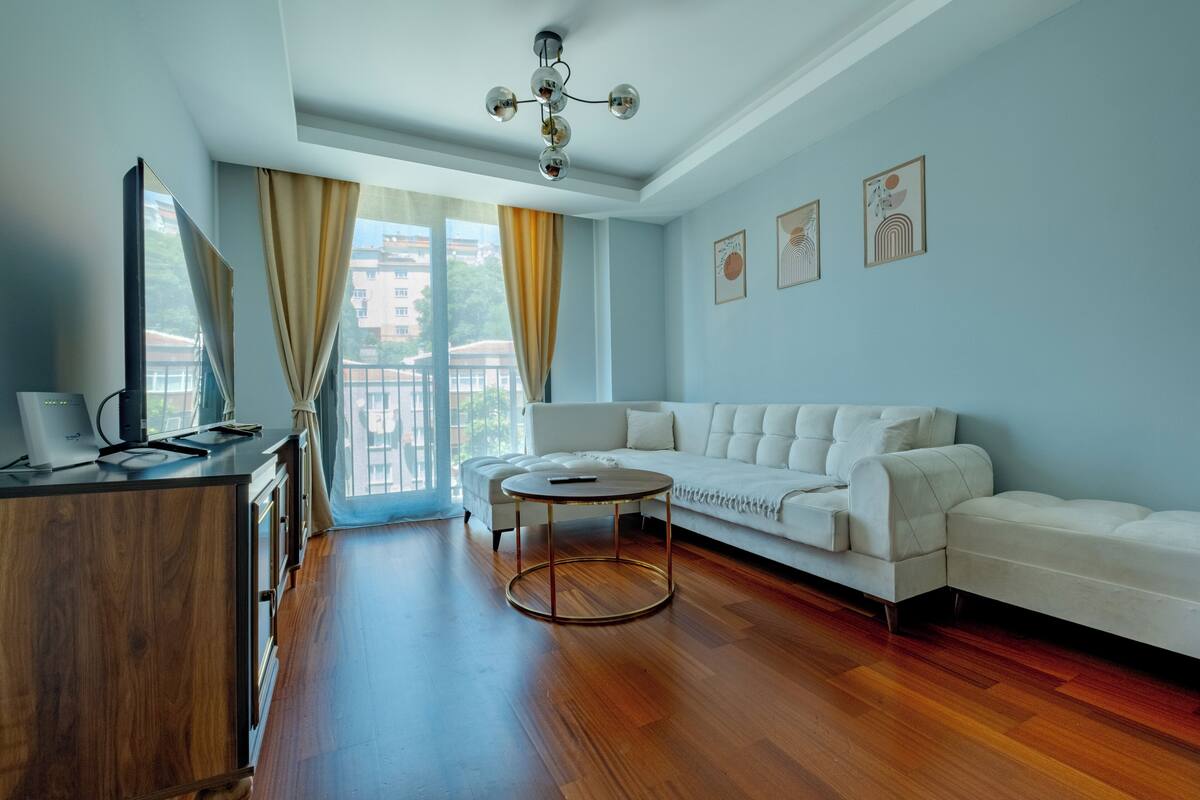 A modern living room with a white sofa, a round coffee table, and a wooden cabinet.