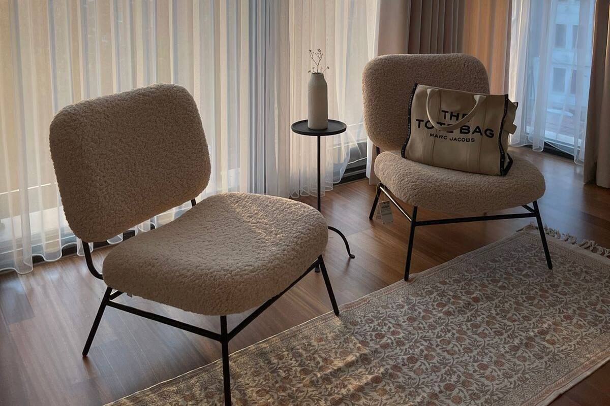 A modern living room with two plush chairs, a small side table, and a patterned rug.