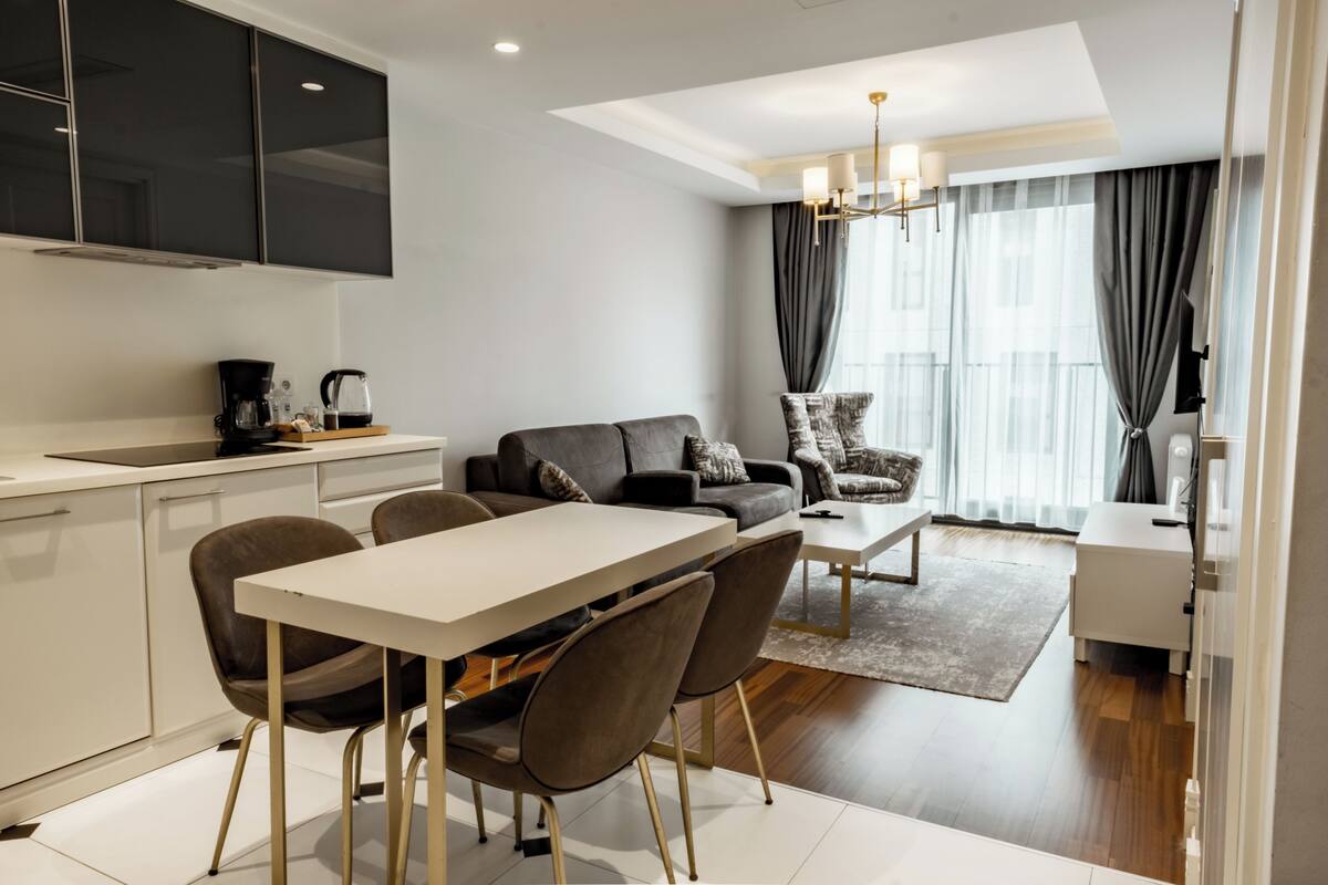 A modern living room with a sofa, coffee table, and dining area.
