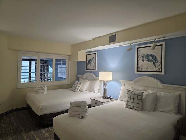 A hotel room with two beds, a nightstand with a lamp, and artwork on the walls. - Oceanfront, 15th floor end unit with amazing views. (North Myrtle Beach)