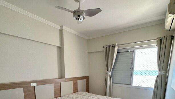 A bedroom with a bed, a ceiling fan, a window with curtains, and a tiled floor. - SEASIDE APARTMENT IN GUILHERMINA (Guilhermina Praia Grande)
