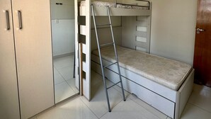 A compact bedroom with a bunk bed, a wardrobe, and a ceiling fan. - SEASIDE APARTMENT IN GUILHERMINA (Guilhermina Praia Grande)