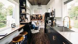 Uma cozinha moderna com esquema de cores preto e dourado, forno embutido e uma janela grande com vista para o exterior.