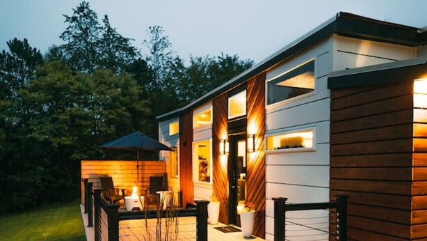 Uma casa moderna com varanda, área de estar externa e entrada bem iluminada.