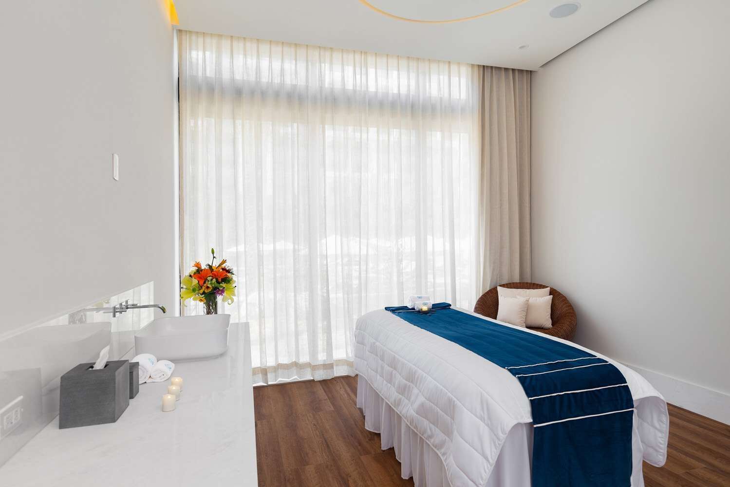 Moderni hotellihuone, jossa on suuri sänky, oleskelualue tuolilla ja pienellä pöydällä sekä kylpyamme.