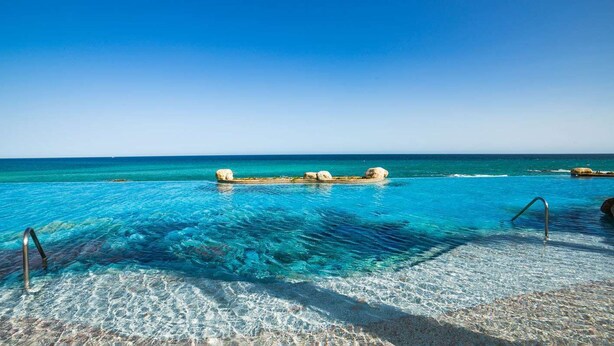 A clear blue pool with a stone border and a metal ladder. - Villa la Valencia  (San José del Cabo)