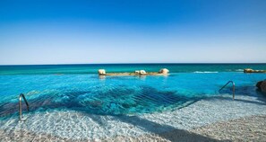 Ein klares, blaues Schwimmbecken mit Steinrand und Metallleiter.