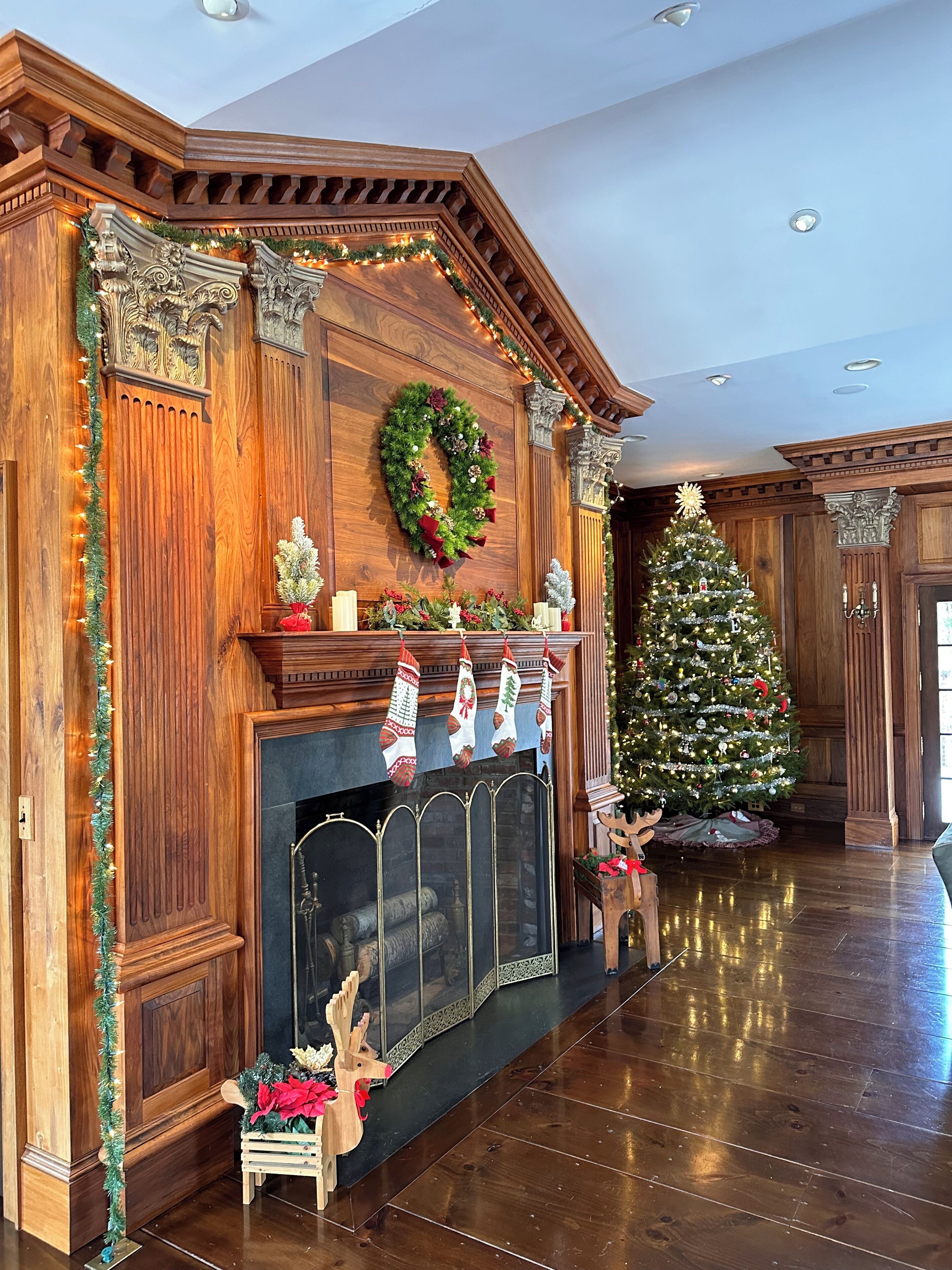 Un salón elegante con chimenea de madera, un árbol de Navidad y decoraciones festivas.