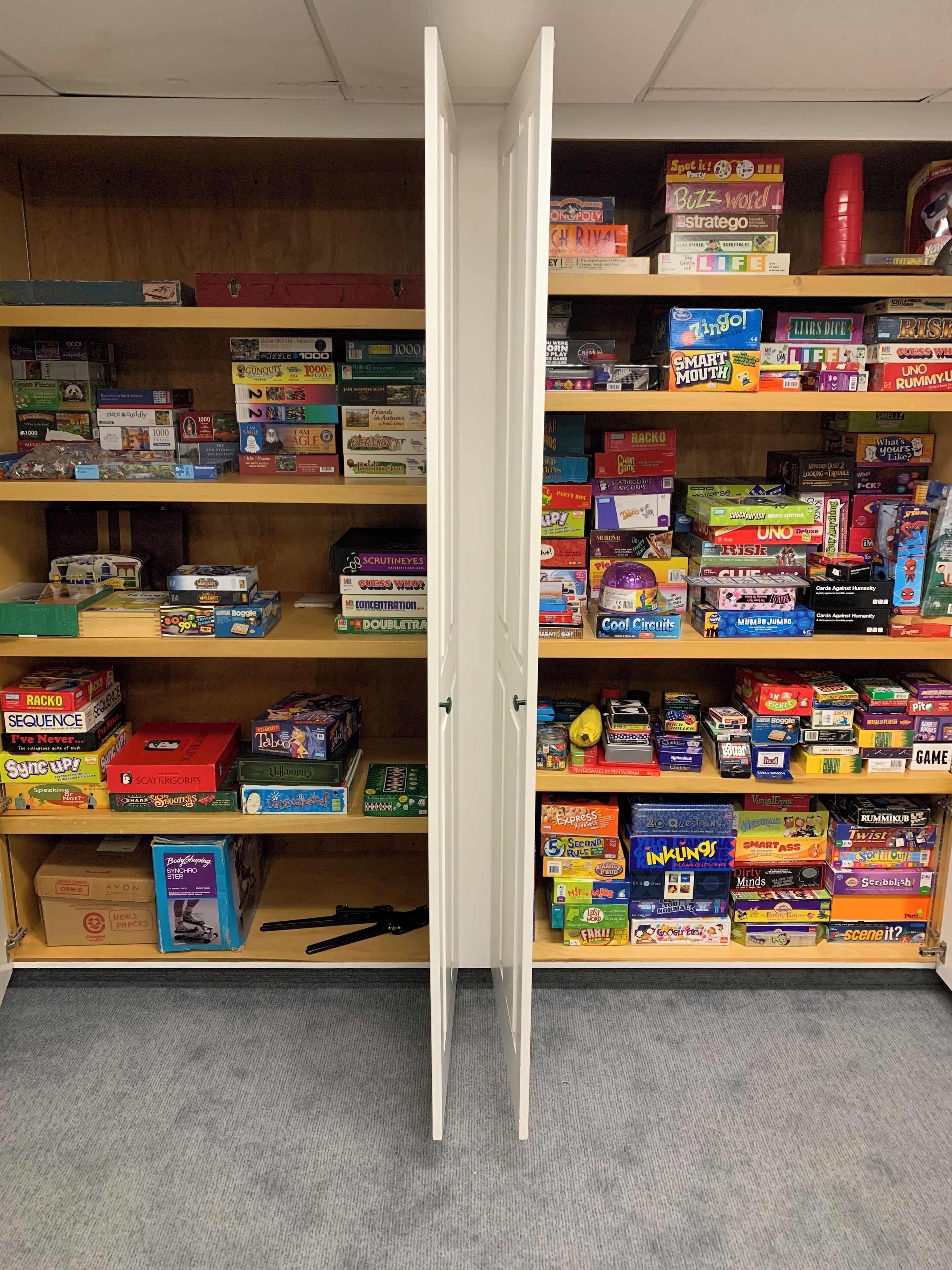 Ein Zimmer mit einem Bücherregal voller verschiedener Brettspiele und einer Tür in der Mitte.