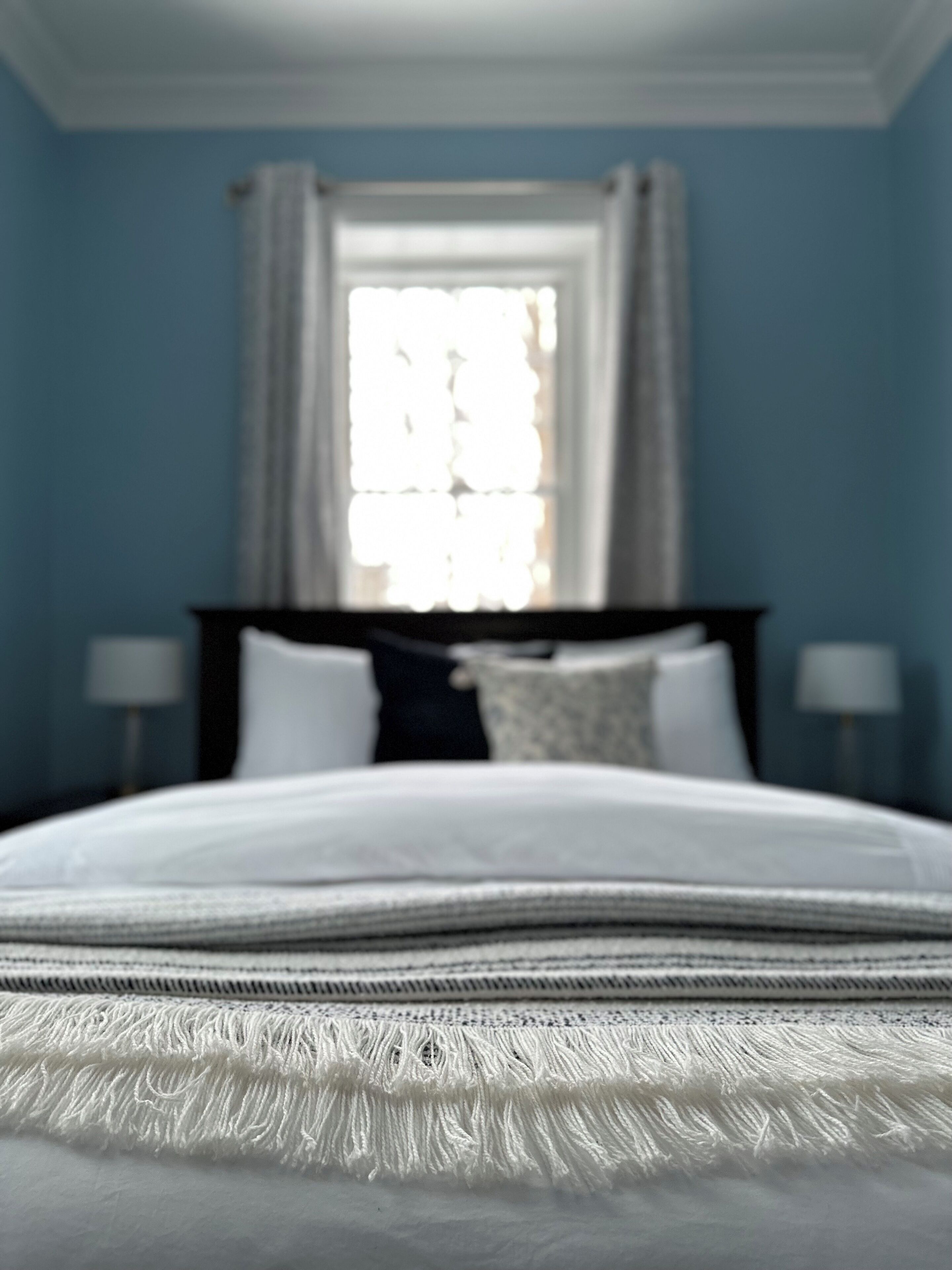 Un dormitorio con una cama, una ventana con cortinas y dos lámparas de noche.