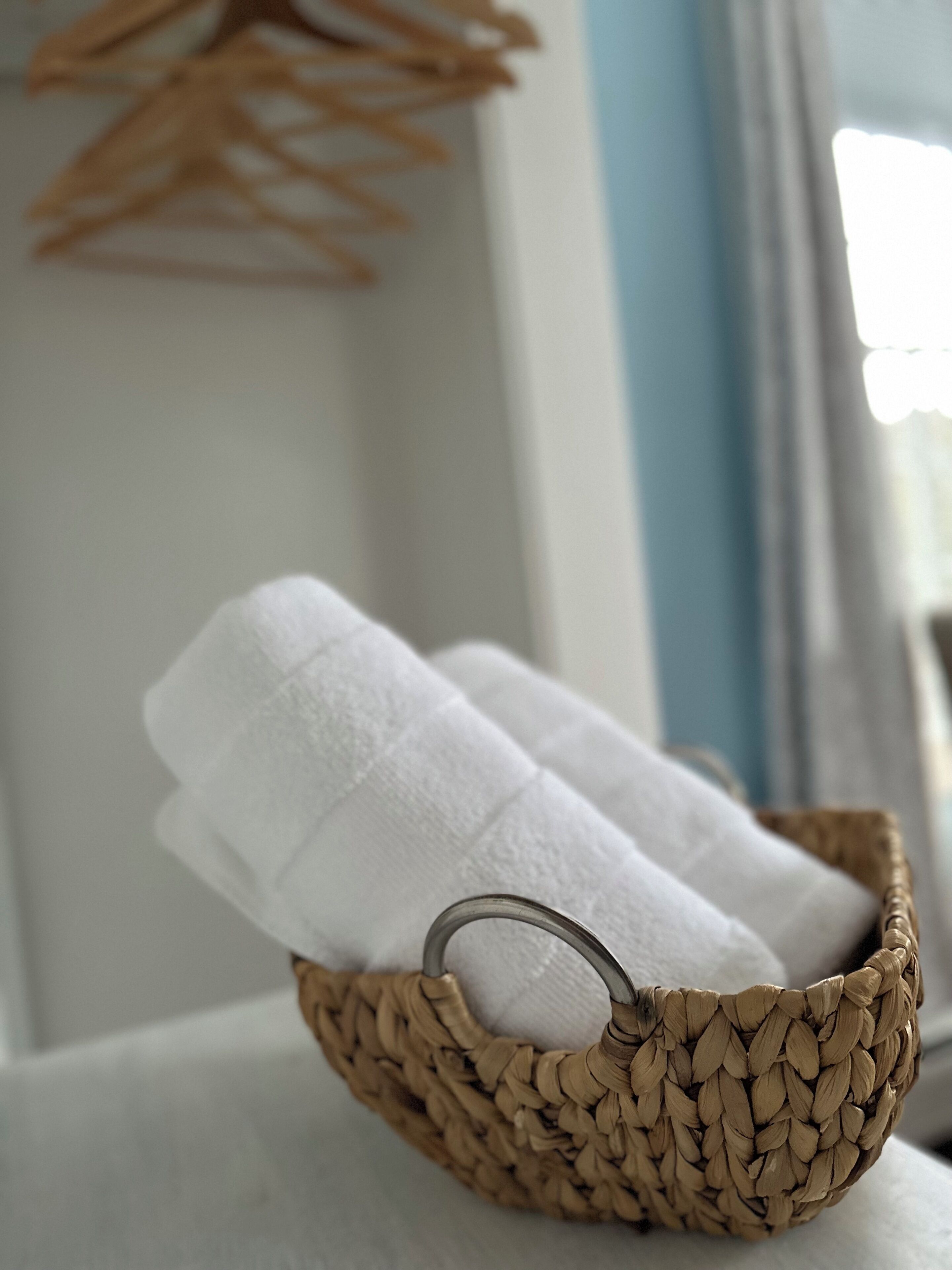 A woven basket containing two white towels on a white surface.