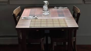 A dining table set for two with a placemat, a glass, and a potted plant with red flowers.