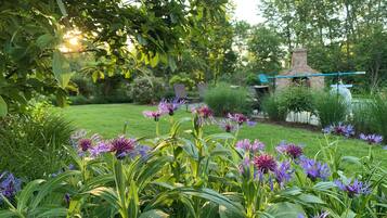 A garden with purple flowers and a stone structure in the background.