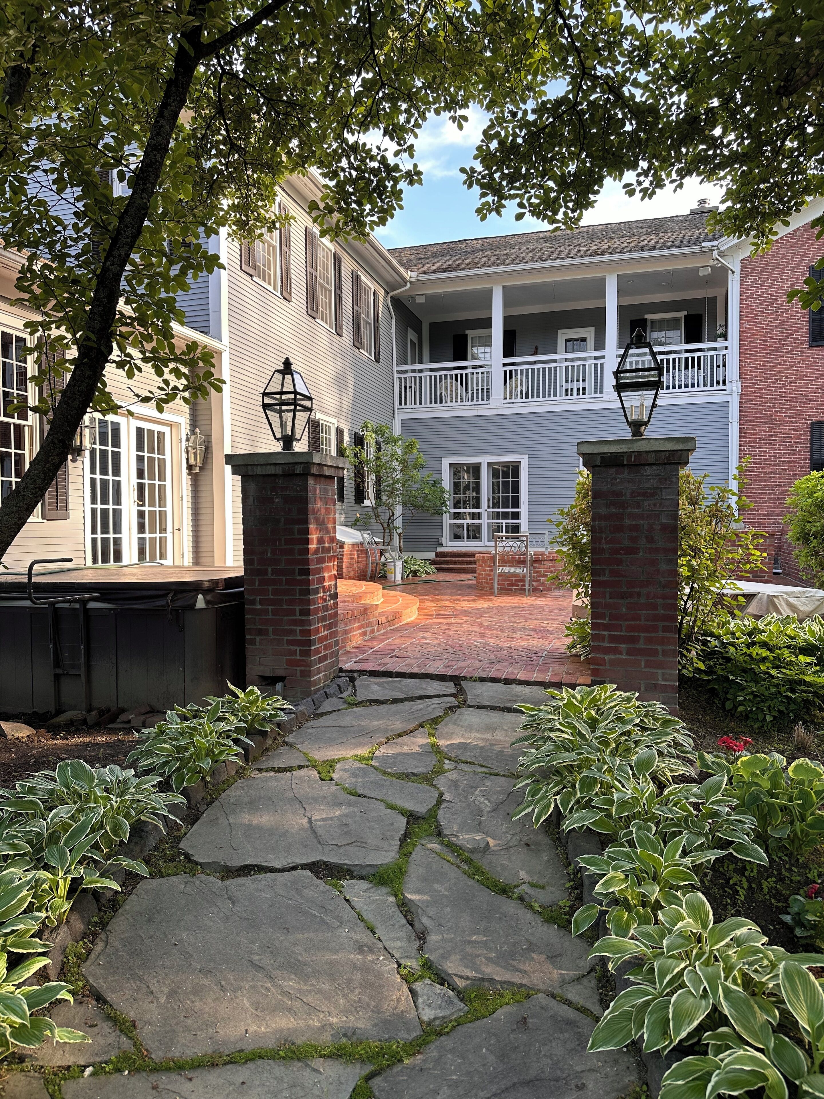 A stone pathway leading to a two-story building with a balcony.