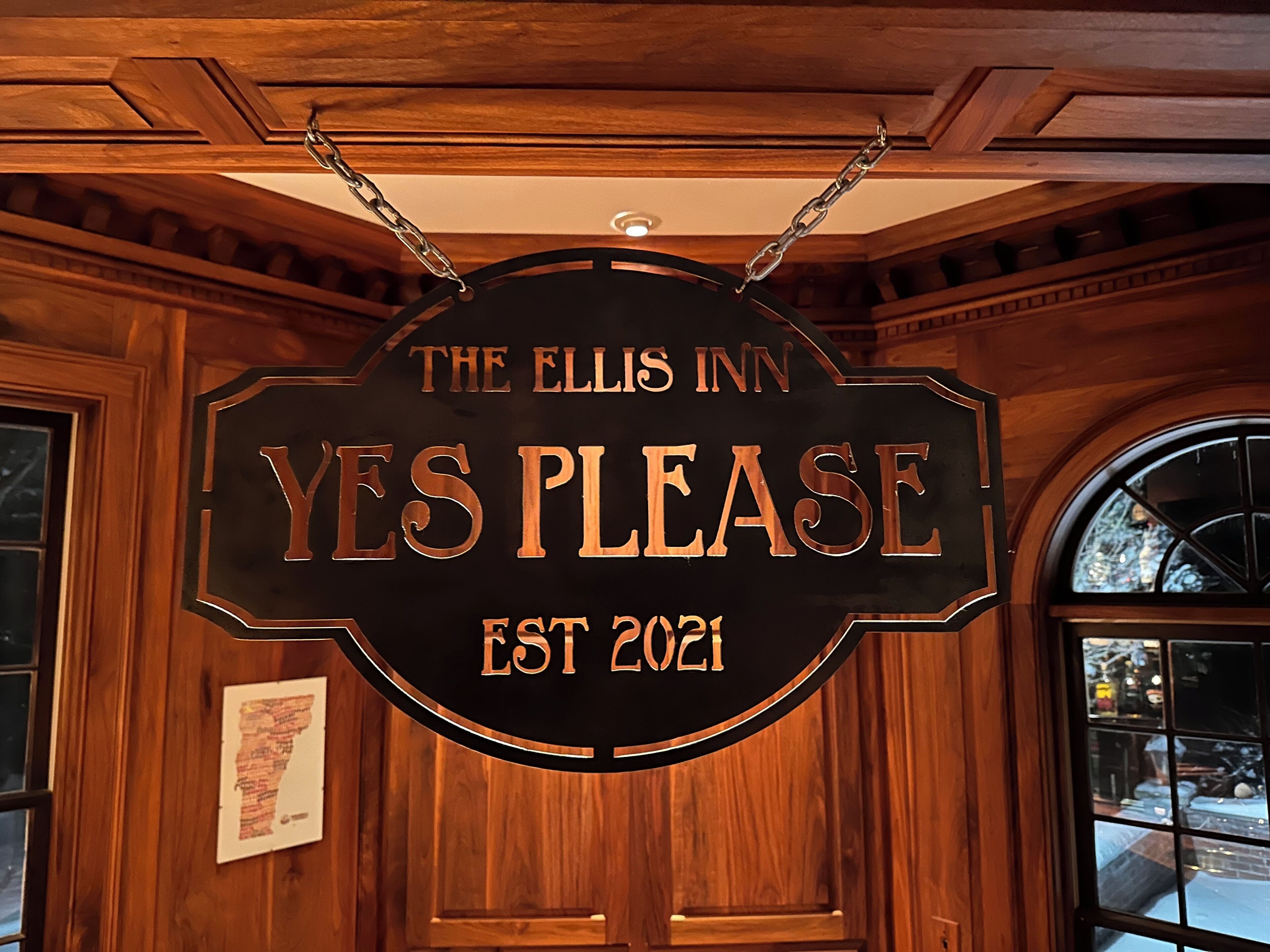 A sign for The Ellis Inn with the words "YES PLEASE" and "EST 2021" on a wooden background.