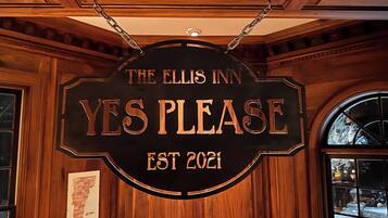 A sign for The Ellis Inn with the words "YES PLEASE" and "EST 2021" on a wooden background.