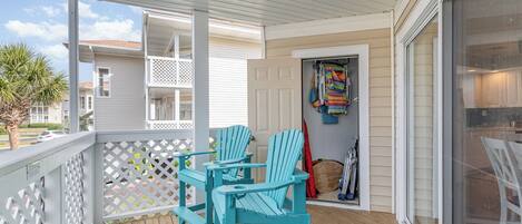 A covered porch with two turquoise Adirondack chairs and a wooden table.