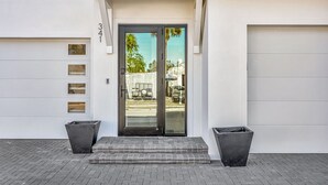 A modern building with a garage door, a double door entrance, and two large planters.