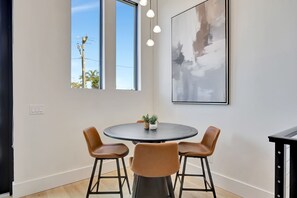 A modern dining area with a round table, two brown chairs, and a potted plant. - New Upscale Retreat Downtown Dunedin w/ Balcony! Sleeps 4 (Dunedin)