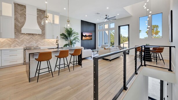 A modern kitchen with a herringbone wood backsplash, a central island with stools, and pendant lighting.