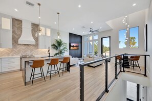 Una cocina moderna con un elegante salpicadero de madera en espiga, una isla central con taburetes e iluminación colgante.