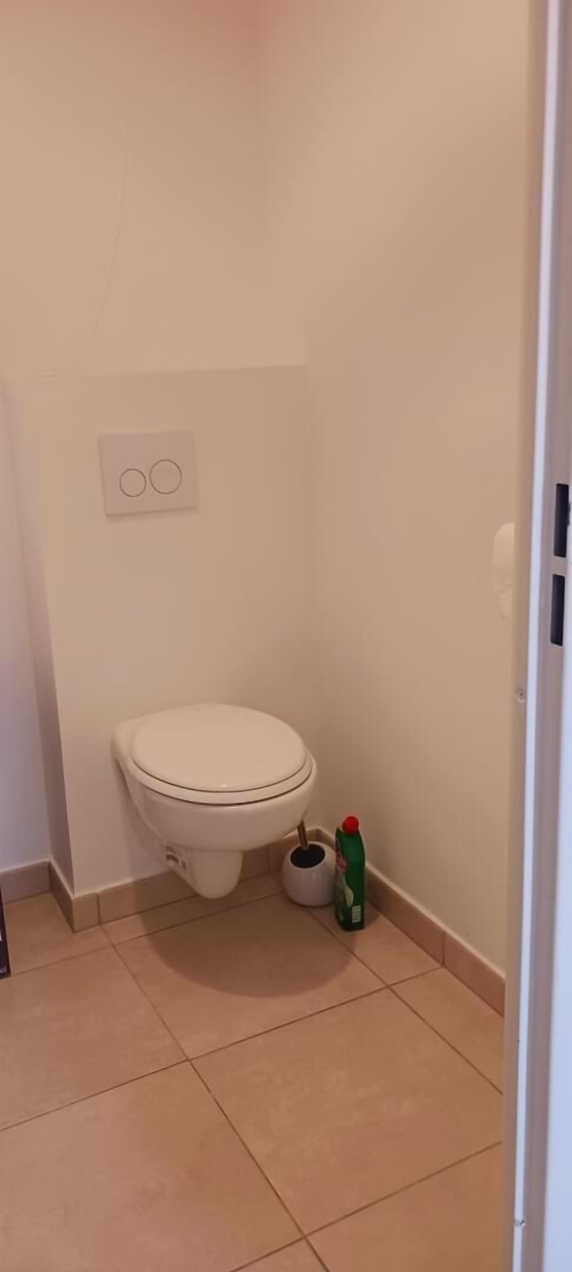 Un baño pequeño y limpio con inodoro, bidé y dispensador de papel higiénico.