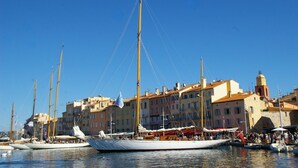 Un port de plaisance où sont amarrés plusieurs voiliers, entouré de bâtiments aux couleurs vives et sous un ciel bleu clair.