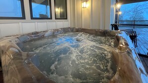 Un bain à remous avec une structure extérieure en bois, une terrasse en bois et une rambarde.