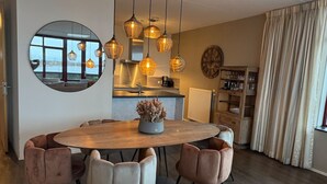 A modern dining area with a round table, six chairs, and hanging pendant lights.