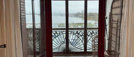 A room with large windows, a hanging wicker lamp, and a view of a dock with boats.
