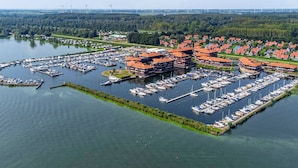 An aerial view of a marina with numerous boats docked, surrounded by residential buildings with red roofs.