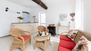 Un salón acogedor con muebles de mimbre, chimenea y una zona de cocina con encimera de piedra.