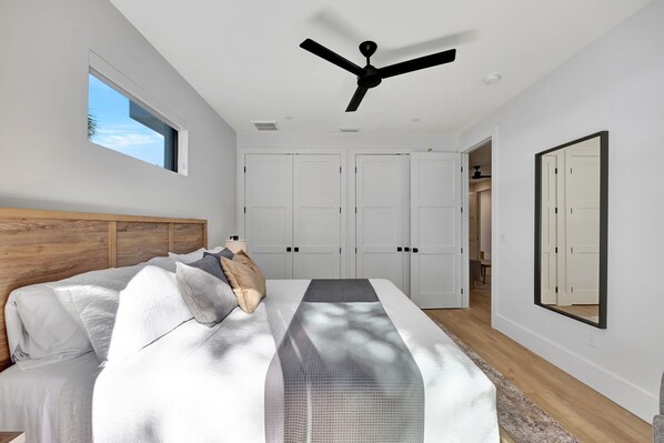 A bedroom with a bed, a ceiling fan, a window, and a wardrobe.