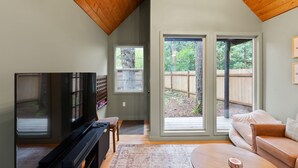 A living room with a television, a sofa, and a large sliding glass door leading to a backyard.